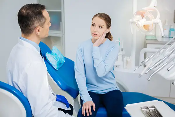 Concerned patient discussing her tooth pain with her dentist while sitting in a dental chair, at Meadowlark Dental in Salem, OR.